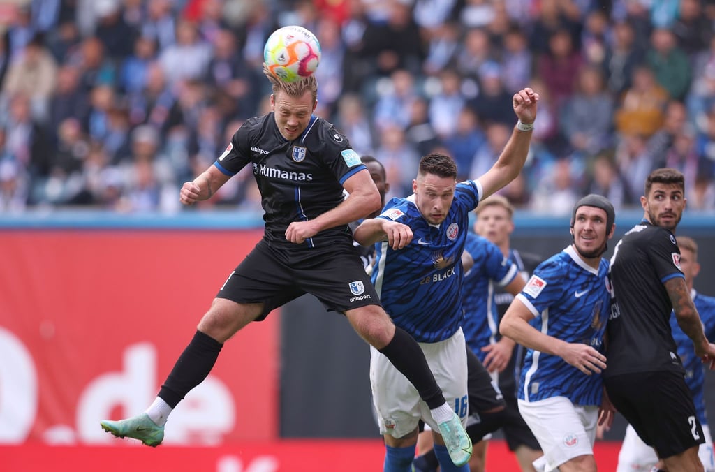 Der Magdeburger Connor Krempicki (l) köpft den Ball vor dem Rostocker Ryan Malone.