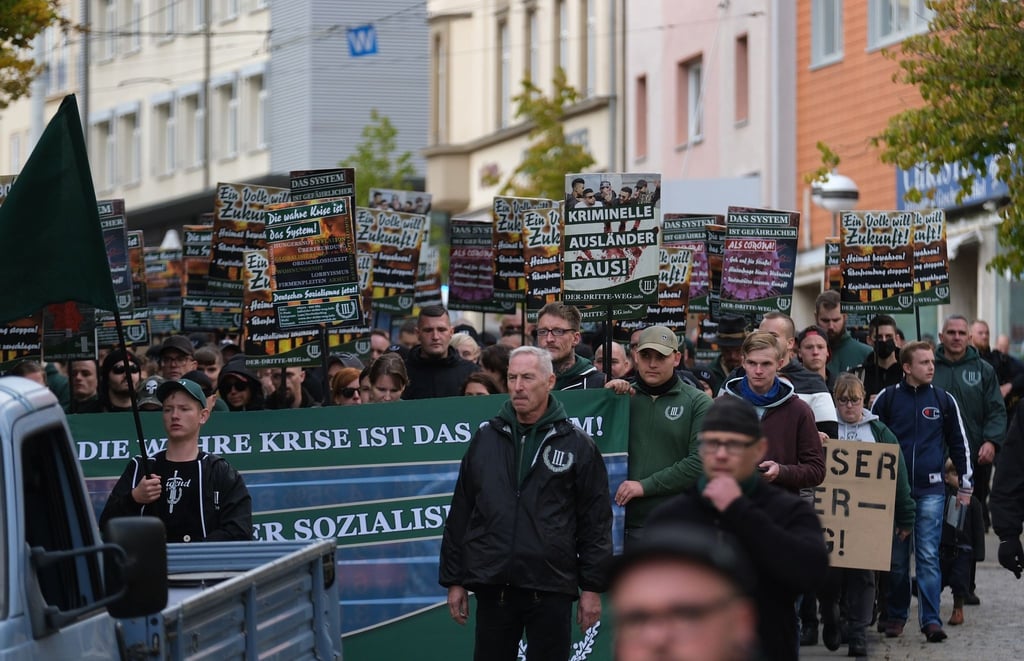 Teilnehmer einer rechten Demonstration gehen eine Straße entlang.
