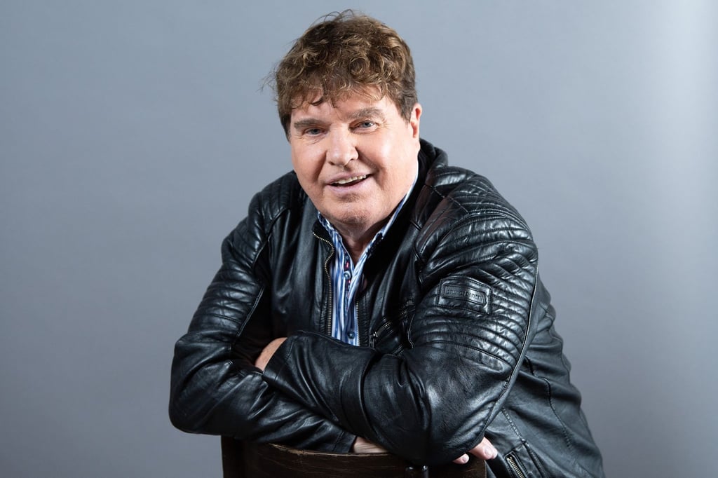 Der Sänger Frank Schöbel sitzt im Boulevardtheater vor einer Fotowand.