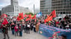 Teilnehmer stehen auf der Demonstration „Heizung, Brot & Frieden! Protestieren statt frieren“ am Potsdamer Platz mit Fahnen und Plakaten.