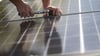 Ein Montuer montiert Photovoltaikmodule auf das Dach eines Wohnhauses.