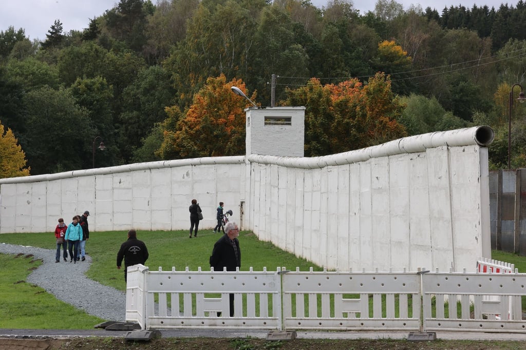 Besucher stehen vor einem Stück Grenzmauer der ehemaligen Staatsgerenze der DDR auf dem Gelände des Grenzmuseums am Rande des Deutschlandfest der CSU zum Tag der Deutschen Einheit.