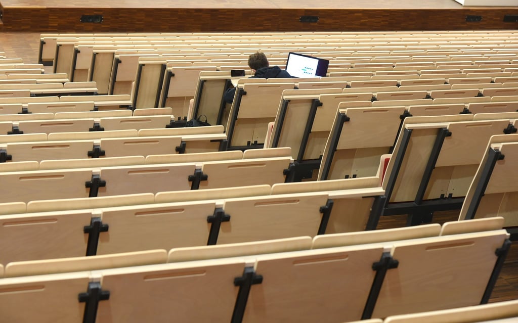 Ein Informatikstudent sitzt bei einer digitalen Vorlesung allein im Auditorium maximum.