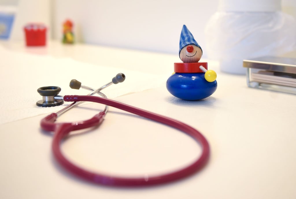 Ein Stethoskop und Kinderspielzeug liegen in einer Kinderarztpraxis auf einem Tisch.