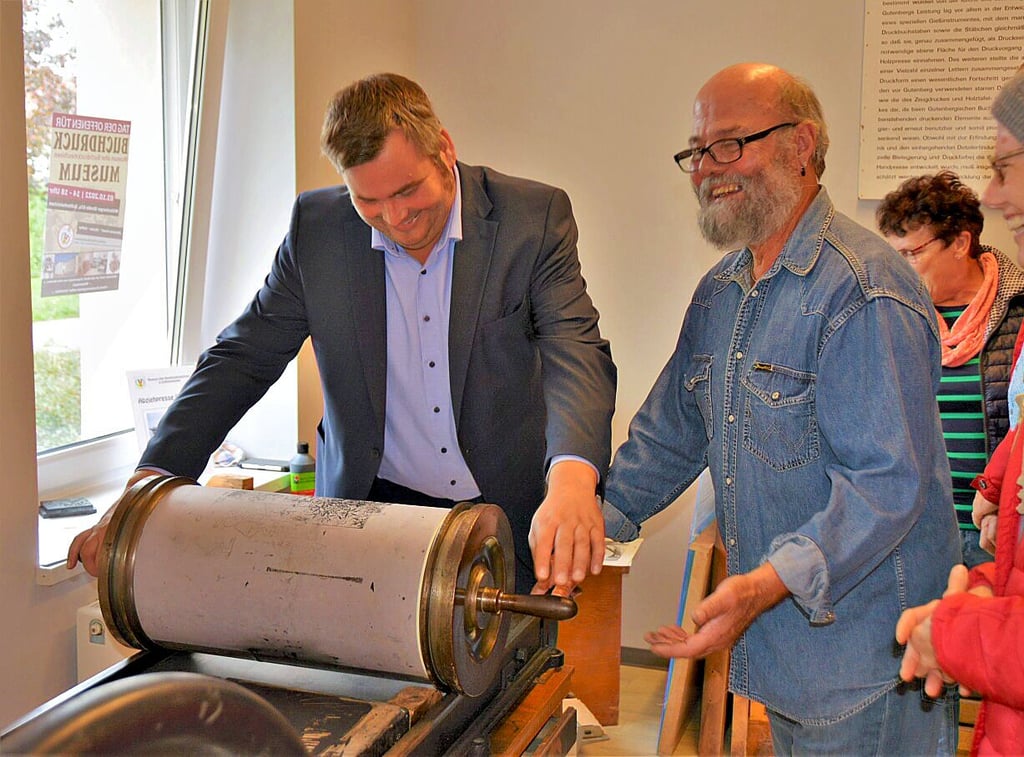 Bürgermeister Enrico Schilling bekommt von Harald Kloth (r.) die Anweisung „Jetzt zieh die Nudel!“. Die „Nudel“ ist die Abziehpresse.