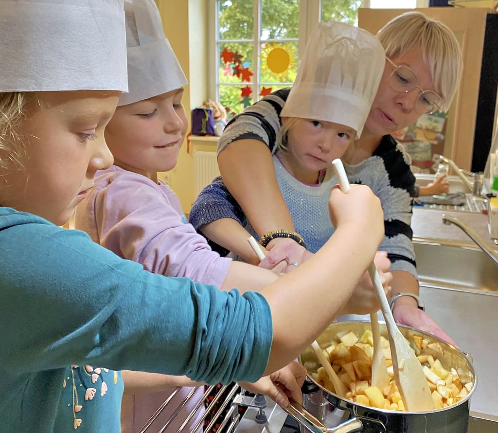 Svea, Alina und Eleonora (von links) bereiten gemeinsam mit Leiterin Saskia Schulze die Äpfel für den Kuchen vor.