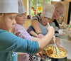 Svea, Alina und Eleonora (von links) bereiten gemeinsam mit Leiterin Saskia Schulze die Äpfel für den Kuchen vor. 