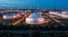 Hinter dem beleuchteten Tanklager ragen die Anlagen der Total-Raffinerie und des Chemieparks in die Höhe (Luftaufnahme mit Drohne).