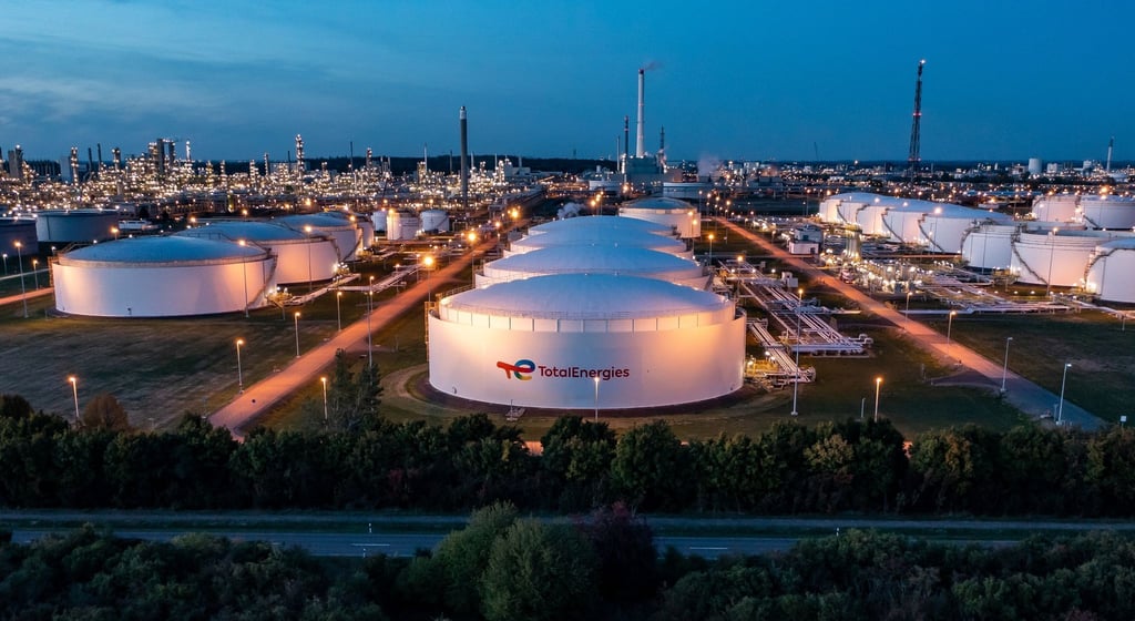 Hinter dem beleuchteten Tanklager ragen die Anlagen der Total-Raffinerie und des Chemieparks in die Höhe (Luftaufnahme mit Drohne).