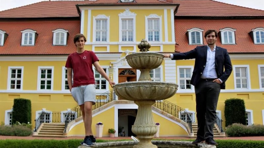 Julius (l.) und Armin von Bismarck auf dem historischen Springbrunnen vor dem Familienschloss in Döbbelin.