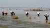 Opfer der schweren Überschwemmungen durch Monsunregen tragen in der Provinz Sindh Hilfsgüter durch das Hochwasser.