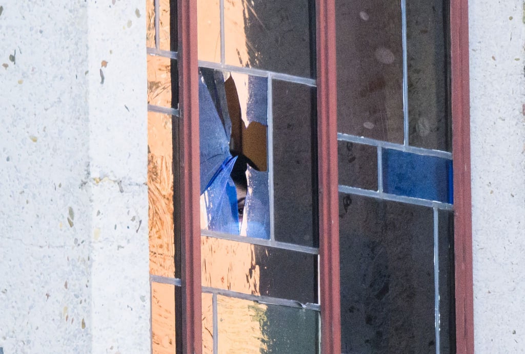 Eine Ermittlerin schaut durch ein beschädigtes Fenster an der Synagoge der Jüdischen Gemeinde.