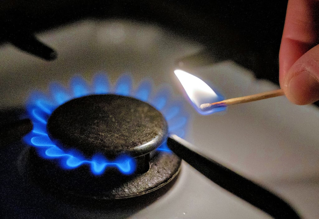 Eine Gasflamme wird auf einem Küchenherd mit einem Streichholz entzündet.