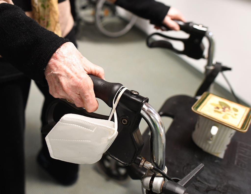 Eine Heimbewohnerin schiebt ihren Rollator mit FFP-2 Maske durch einen Gang in einem Altersheim. Die aktuell geltende FFP2-Maskenpflicht für Bewohner in Pflege- und Wohneinrichtungen steht in der Kritik – auch in Magdeburg.
