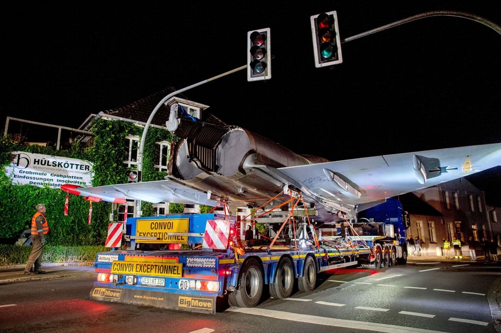Schwertransporter fährt mit einem Kampfflugzeug vom Typ Eurofighter Typhoon durch das Stadtzentrum.