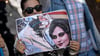 Eine Iranerin beteiligt sich in Frankfurt an einer Demonstration gegen das politische Regime im Iran. Dabei hält sie ein Plakat mit dem Bild der 22-jährigen Mahsa Amini in den Händen.