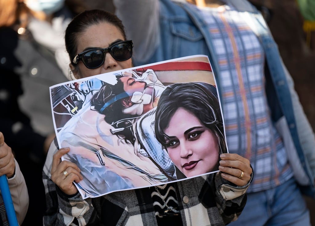 Eine Iranerin beteiligt sich in Frankfurt an einer Demonstration gegen das politische Regime im Iran. Dabei hält sie ein Plakat mit dem Bild der 22-jährigen Mahsa Amini in den Händen.