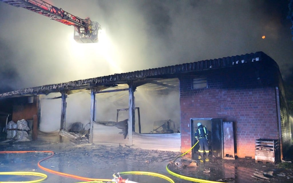 Feuerwehrleute löschen an einer Halle.
