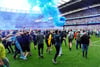 Fans von Manchester City stürmen das Spielfeld und jubeln über den Gewinn der englischen Meisterschaft.