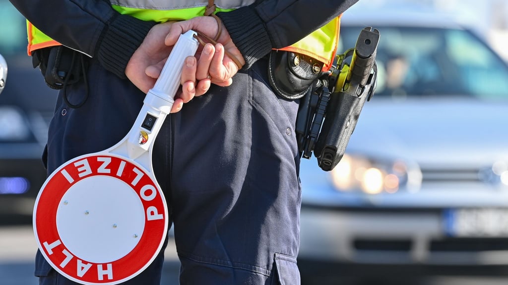 Ein Polizeibeamter hält eine Winkerkelle in den Händen.