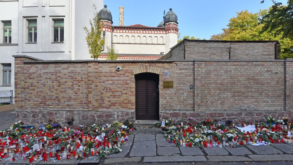 Blumen und Kerzen stehen neben der Tür zur Synagoge.