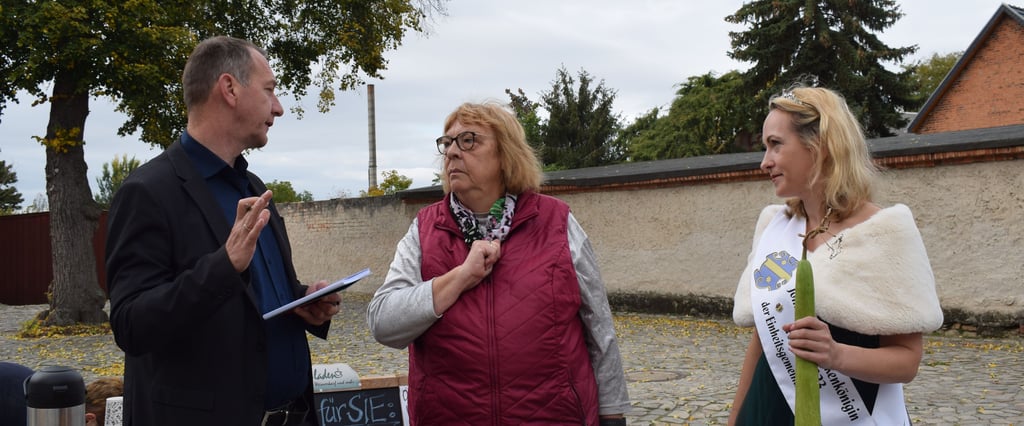 Bürgermeister Jens Hünerbein und Gurkenkönigin Catherina I. im Gespräch mit Marita Dressel, Vorsitzende des Fördervereins Kirche St. Paulus und Kirchberg Menz. Sie hatte mehrere Hinweise dabei, die ihr als Radfahrerin aufgefallen waren.