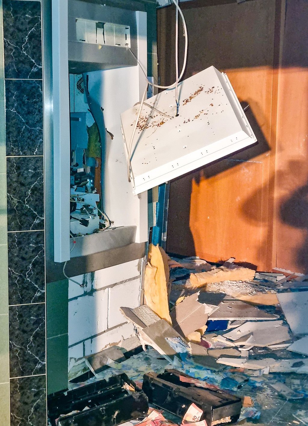 Nach der Explosion in Rieder: Der Geldautomat ist zerstört, Teile der Raumverkleidung liegen auf dem Boden, dazwischen Geldscheine.