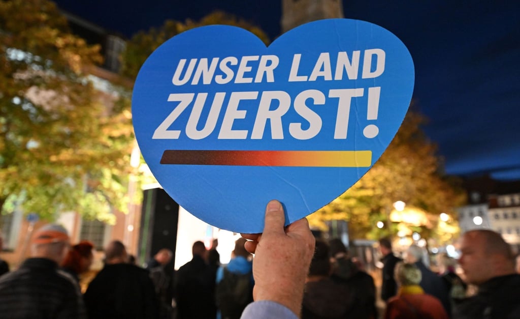 Ein Mann hält ein Herz mit dem Aufdruck „Unser Land zuerst!“ während einer AfD-Kundgebung neben der Georgenkirche.