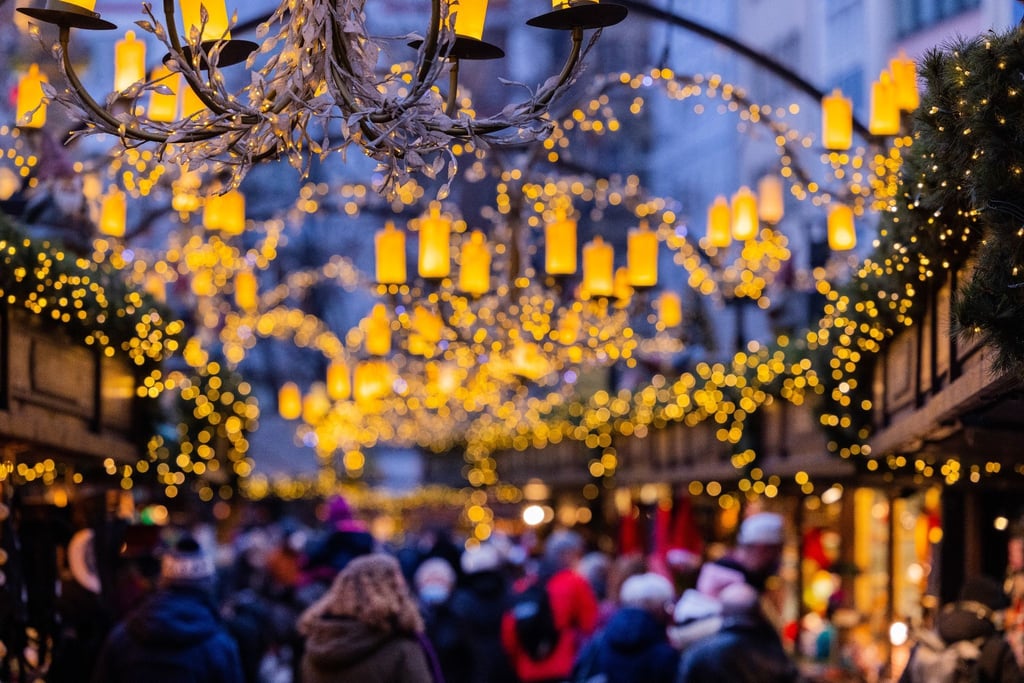 Besucher gehen über einen Weihnachtsmarkt.