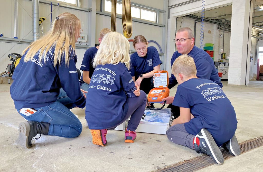 Heiko Winzer zeigt den Mitgliedern der Kinder- und Jugendfeuerwehr, was sich in einem Notfallkoffer befindet.