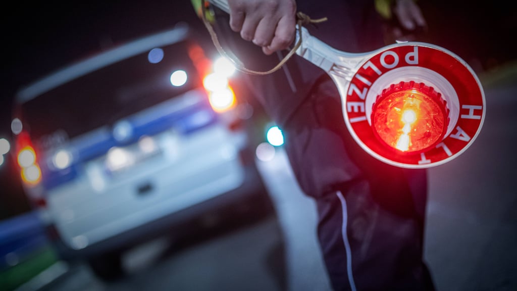Ein Polizist hält bei einer Kontrolle eine Haltekelle in der Hand (Symbolfoto).
