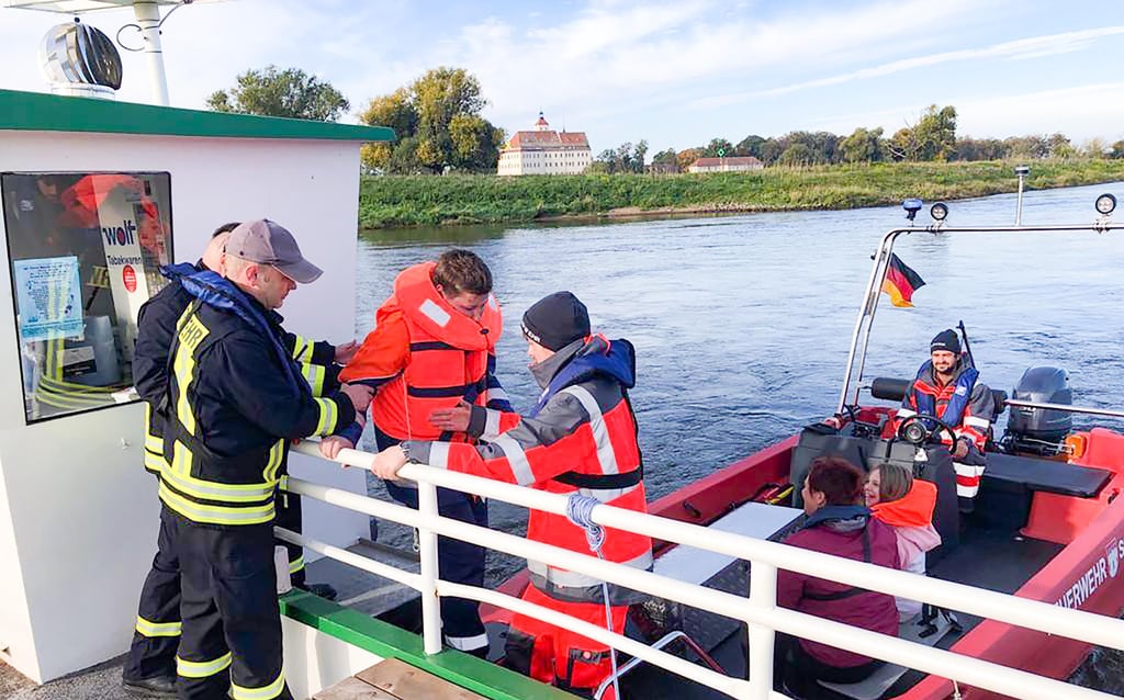 Vorsichtig wird den Kindern von Feuerwehrleuten über die Reling der Fähre Mauken - Pretzsch ins Boot geholfen.