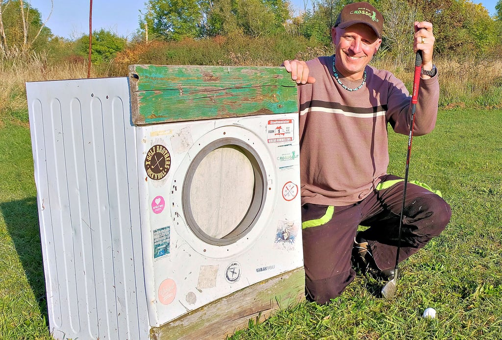 Nationalspieler Mario Prell neben der berühmten Waschmaschine. Sie dient bei Crossgolf-Turnieren in Elster als Ziel.