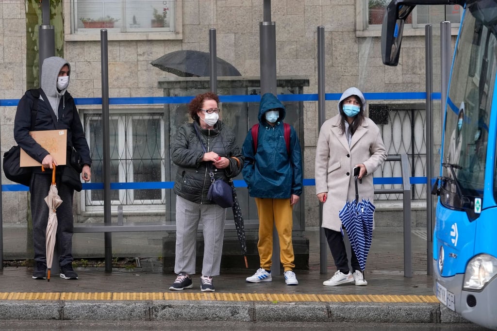 Menschen warten im April 2022 mit Masken vor dem Einsteigen in einen Bus in Madrid.