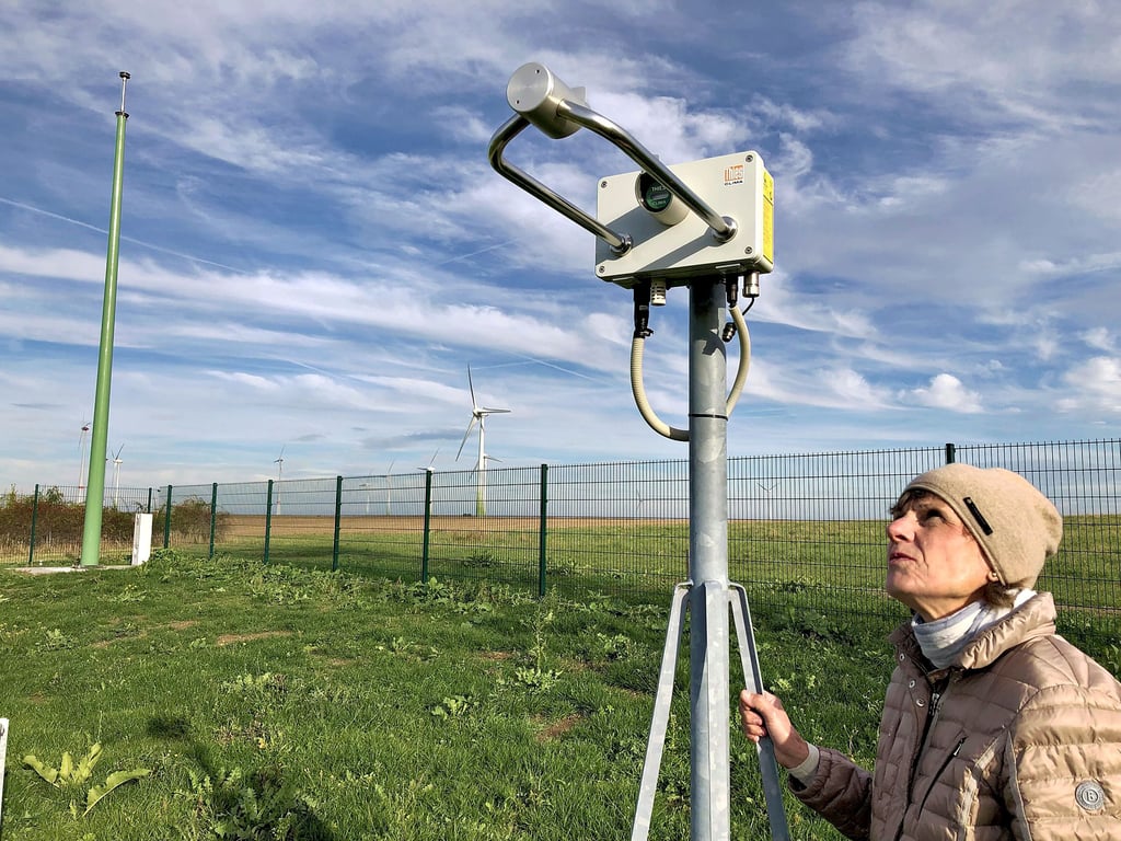 Wetterfachkraft Petra Fude betrachtet in der Osterfelder Wetterstation den Laserniederschlagsmonitor. Mit diesem Gerät kann die Niederschlagsart und der aktuelle Wetterzustand bestimmt werden. Die Station wurde in den vergangenen Monaten modernisiert, der Abstand zu den Windrädern (hinten links im Bild) ist gerade ausreichend, um die aufgezeichneten Daten nicht zu verfälschen.
