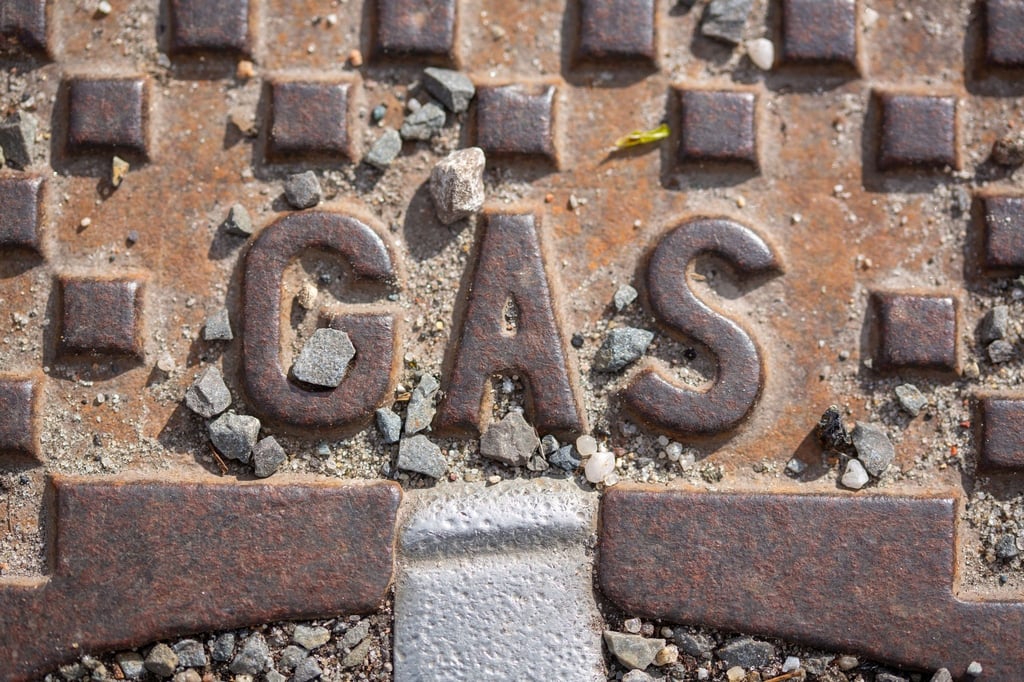 Der Schriftzug „Gas“ steht auf einer Straßenkappe.