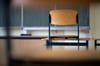 Ein Stuhl steht in einem Klassenzimmer auf dem Tisch.