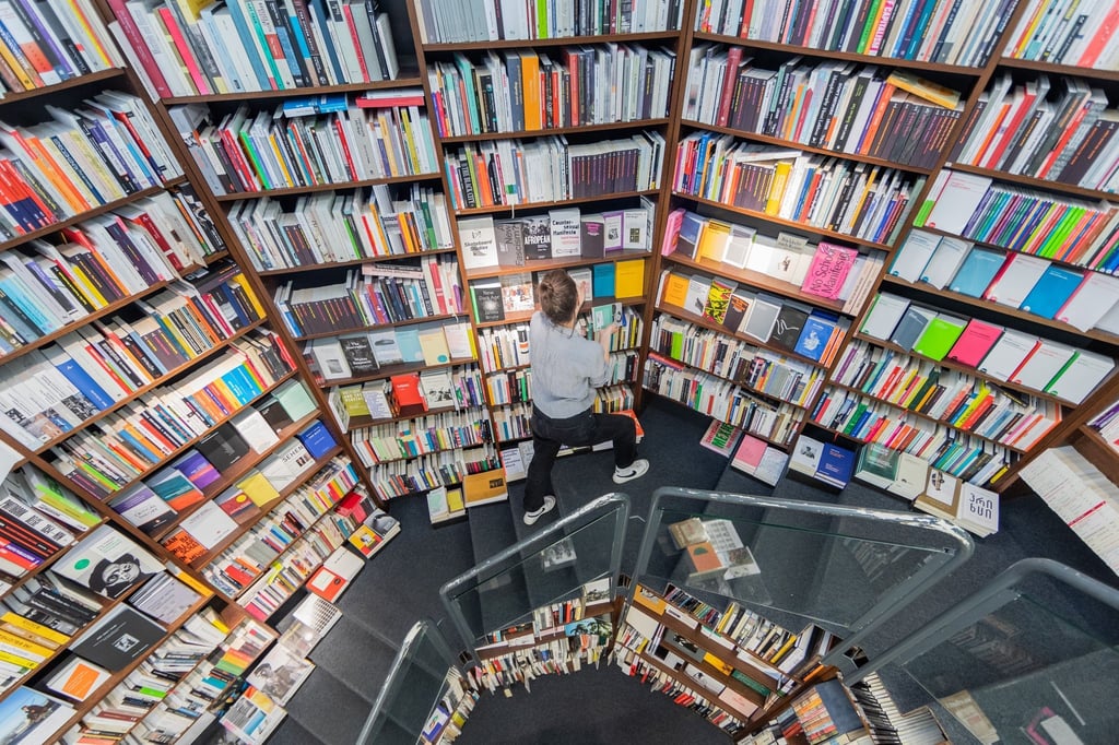 Eine Frau sortiert Bücher in die Regale einer Buchhandlung ein.