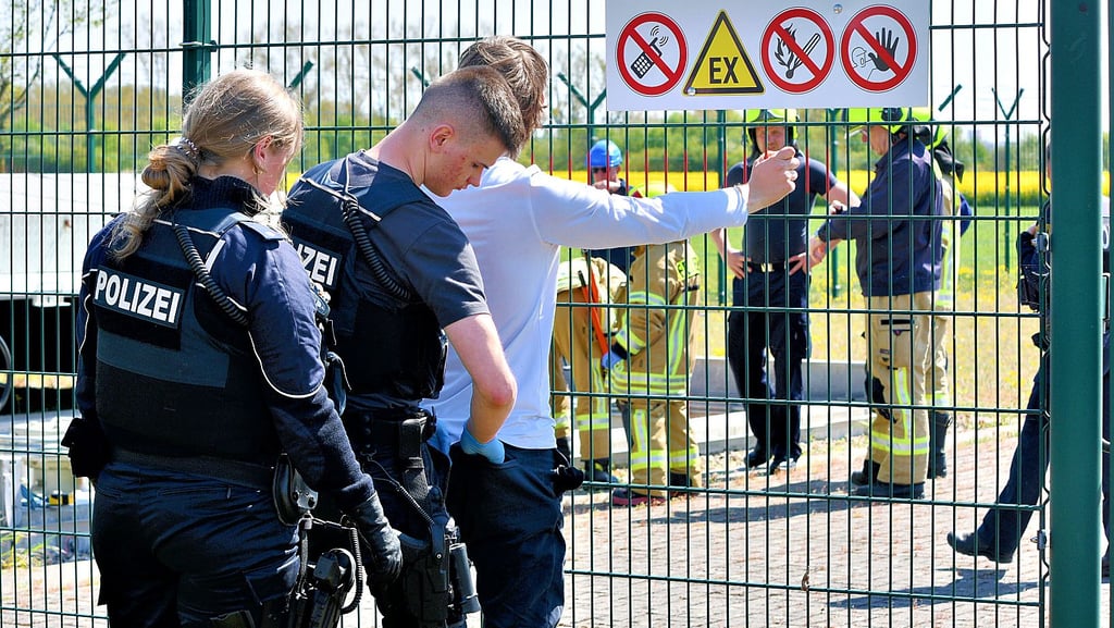 Nach der Störaktion untersuchen Polizeibeamte einen der Umweltaktivisten. Für ihn und seinen Partner wird das Ganze keine Konsequenzen haben.