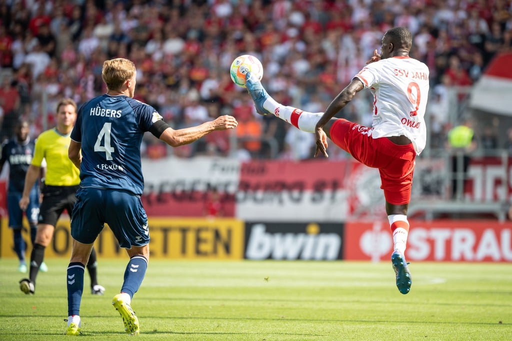 Kölns Timo Hübers (l) und Regensburgs Prince Osei Owusu im Zweikampf um den Ball.