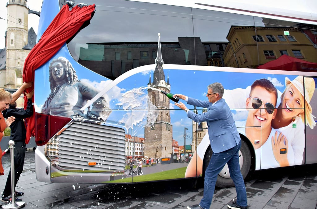 Bürgermeister Egbert Geier bei der Bus-Taufe mit Sekt: Das Fahrzeug aus Linz wirbt jetzt mit Halle-Motiven für die Saalestadt.