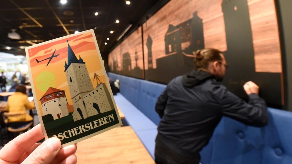 Grafiker Silvio Merkwitz signiert seine Aschersleben-Silhouetten an der Wand des Cafés. Dort wird auch seine neue Postkarte Platz finden.