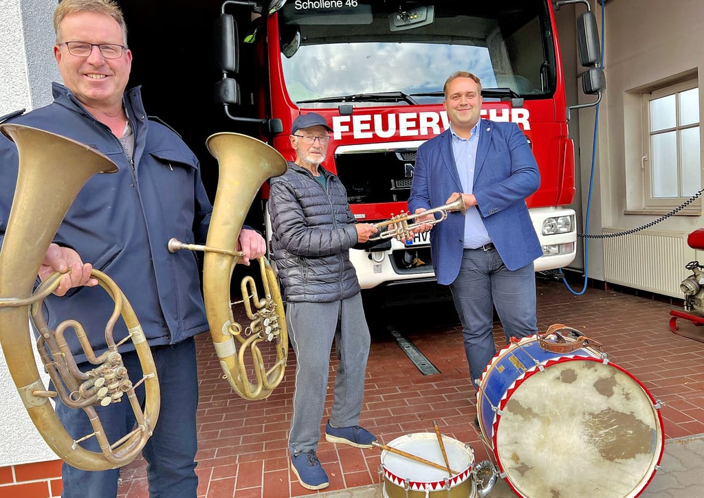 Symbolische Staffelstab-Übergabe in Schollene: Der ehemalige Kapellenleiter Edgar Musow überreicht seine Trompete an Sebastian Engel, der die Kapelle wiederbeleben möchte. Wehrleiter Uwe Engel will dabei unterstützen.