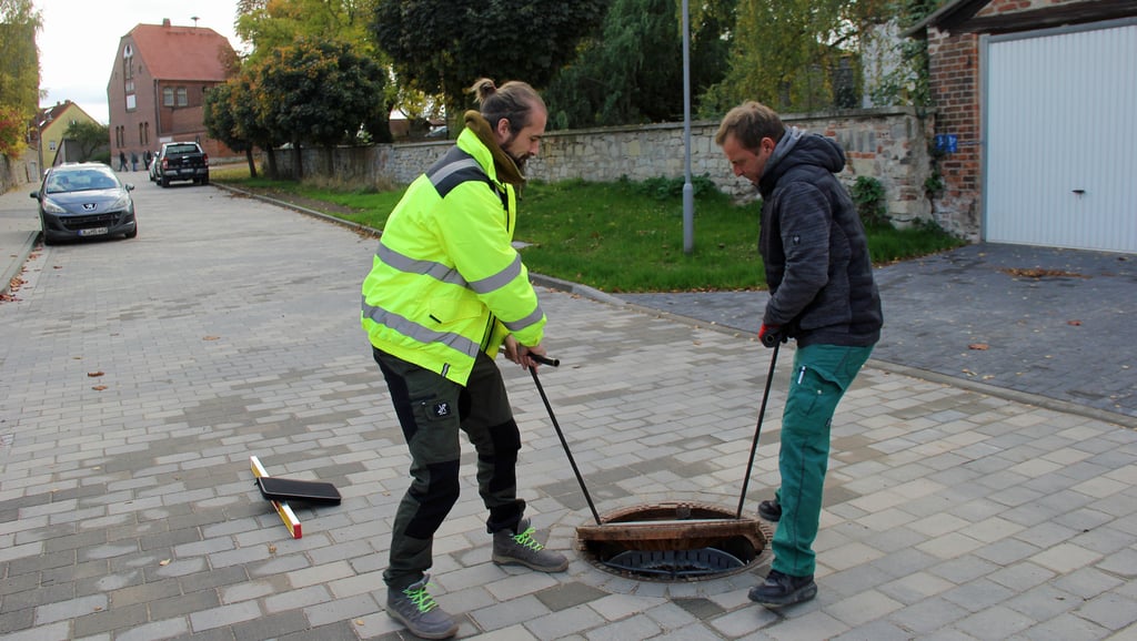 Abschlussprüfung: Planer Daniel Lehmann (links) und Polier Michael Künzelt nehmen während der Bauabnahme einen Schacht zum Regenwasserkanal in Augenschein.