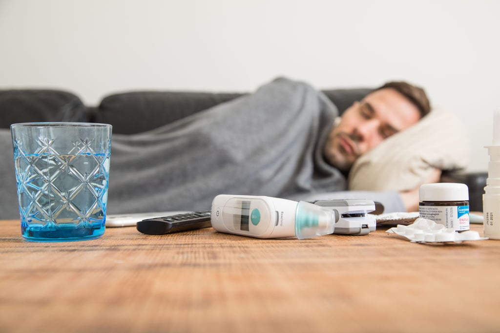 Ein Mann liegt krank auf dem Sofa und schläft.