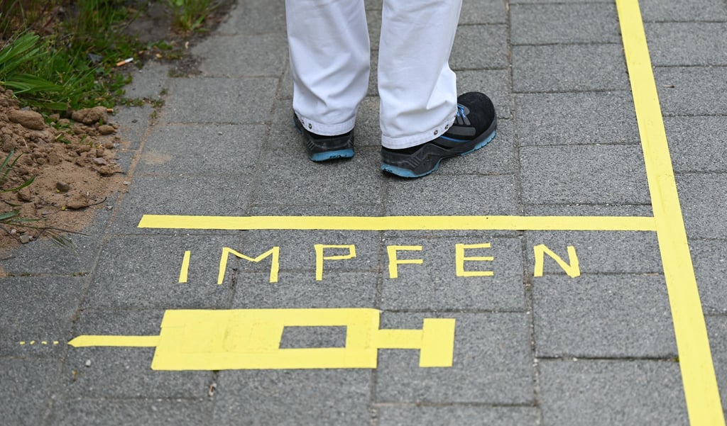 Ein Mann steht an einem Covid-19-Impfcenter hinter der Bodenaufschrift "Impfen".