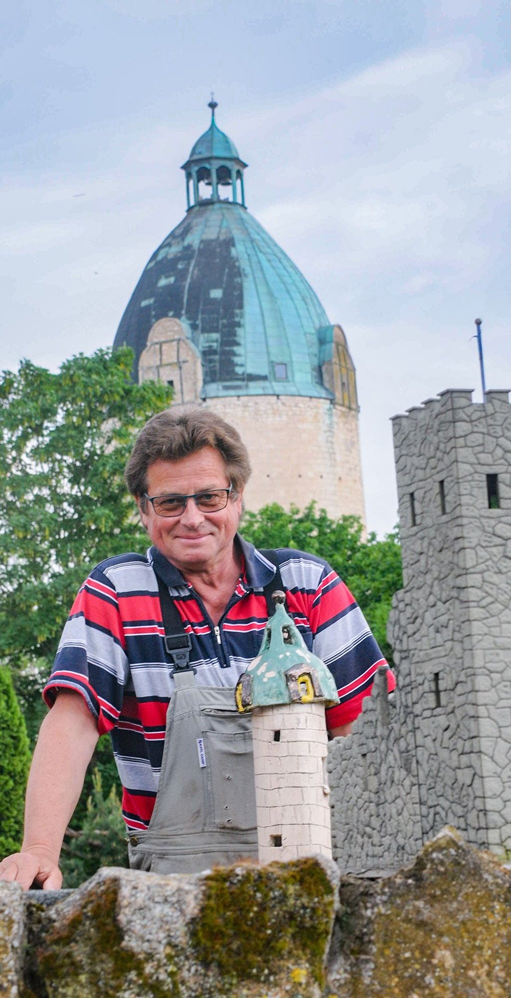 Roland Cebulla steht an der Miniatur des „Dicken Wilhelm“, die er einst als Geburtstagsgeschenk erhielt - im Hintergrund ist das Original zu sehen.