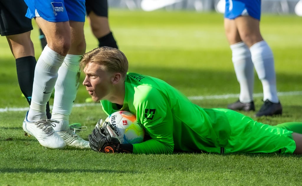 Torwart Oliver Christensen von Hertha BSC hält einen Ball am Boden.