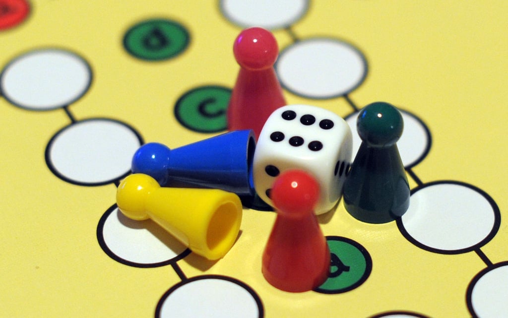 Spielfiguren liegen am auf einem „Mensch ärgere dich nicht!“ Spielbrett.