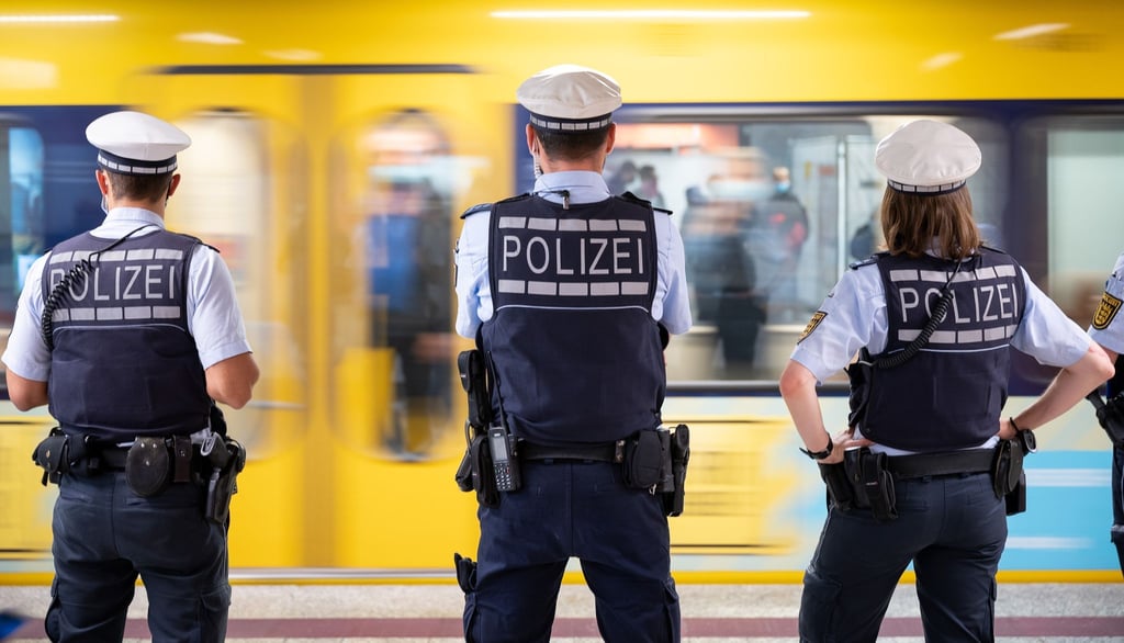Polizeibeamte kontrollieren an einer Haltestelle im öffentlichen Nahverkehr die Einhaltung der Maskenpflicht.